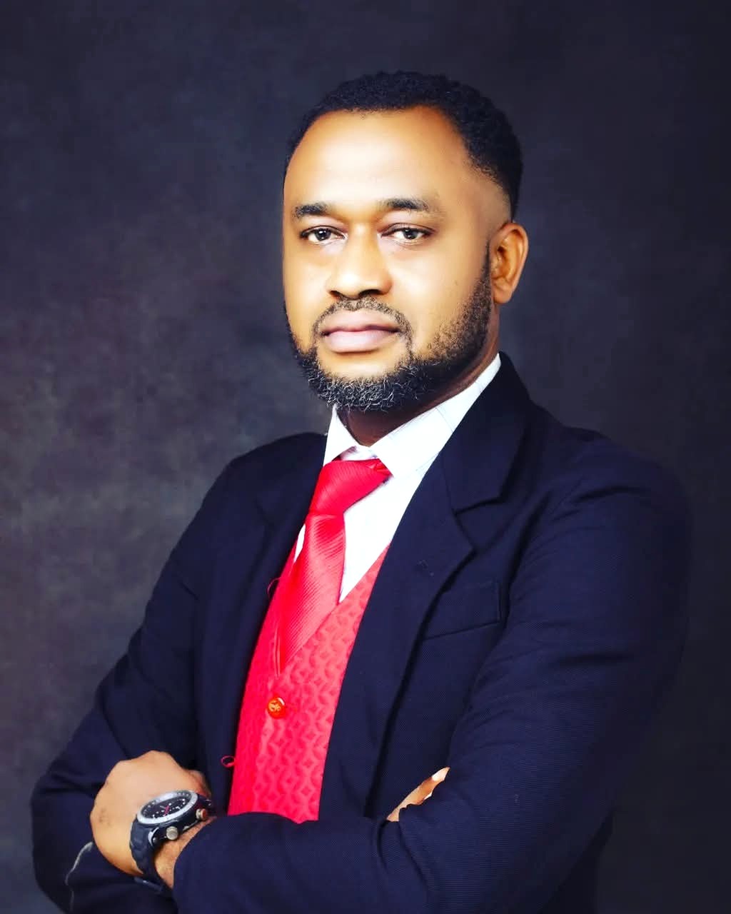 Evangelist Esosa Gift, Youth Pastor, wearing a navy suit and red tie